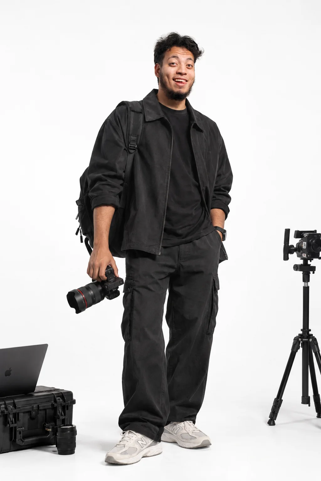 Mustafa Ibrahim holding a camera in a studio, next to a tripod and a laptop