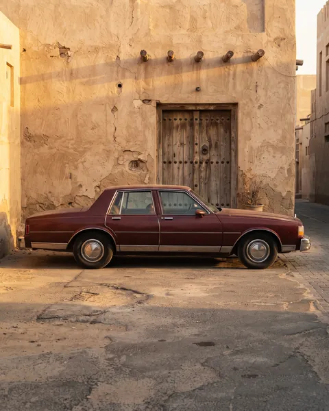 Classic sedan parked by an old Kuwaiti house